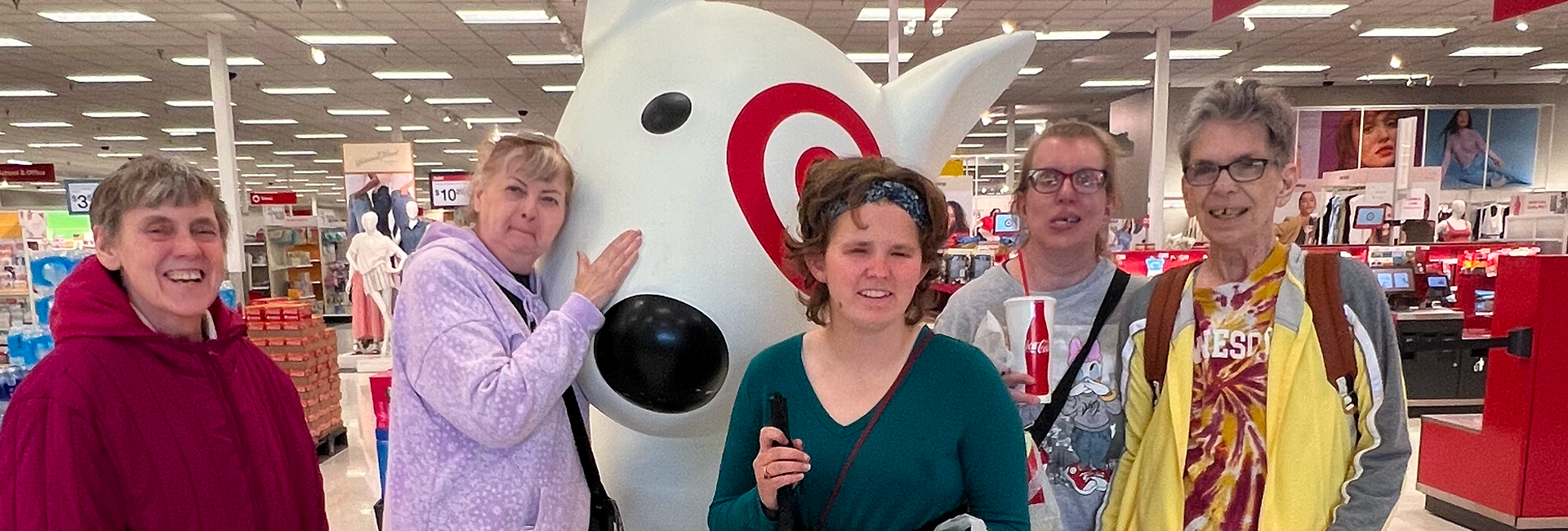 Three people posing with a large Target mascot indoors.