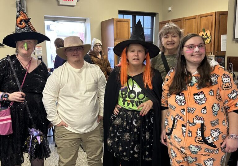 Five people dressed in Halloween costumes pose indoors.